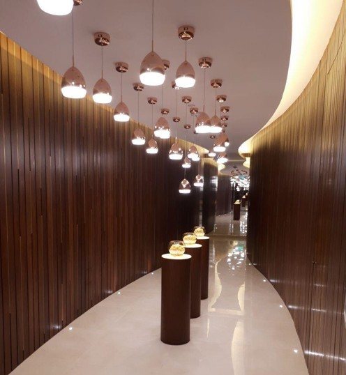 Arrival corridor — cascading copper pendants & curved timber wall